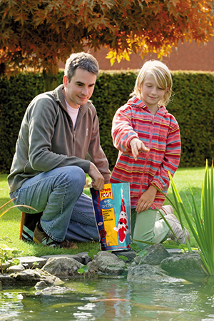 Man and child feeding pond fish